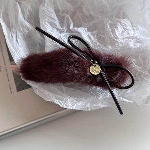 Vue détaillée d'une pince à cheveux en peluche bordeaux avec pendentif en métal doré