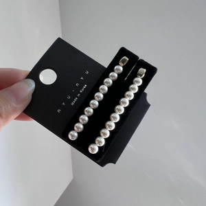 Détail de boucles d'oreilles minimalistes avec perles blanches sur carte de présentation