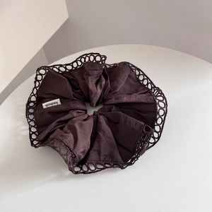 Detail of dark coffee scrunchie with hollow lace edge and handmade fabric label