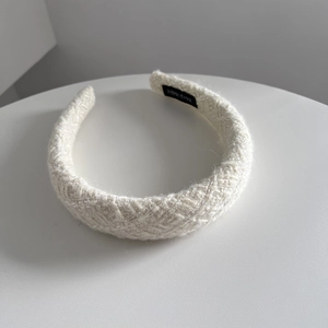 Detailed knit texture of cream white headband featuring a black handmade woven label