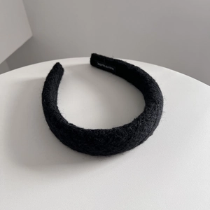 Detail of black wool knit headband showing thick fuzzy texture and handmade woven label