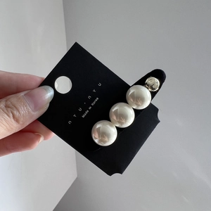 Détail de la pince à cheveux avec grandes perles blanches et bille métallique dorée