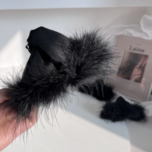 Detailed view of elegant black feather hair claw clip with soft plush satin textures