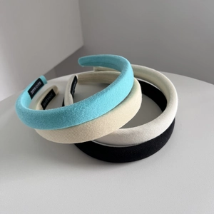 Three minimalist high-top padded headbands in cream white, sky blue, and classic black