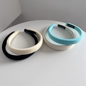 Detail showing high crown fabric headbands in black, beige, blue and white with handmade labels