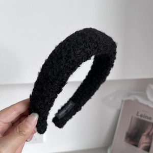 Close-up of black fleece headband featuring handmade label and fluffy texture detail