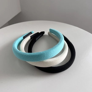 Detailed view of handmade thick fabric headbands in blue, white, and black colors