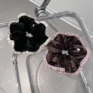 Détail de chouchous en velours avec bords à volants et petits ornements métalliques