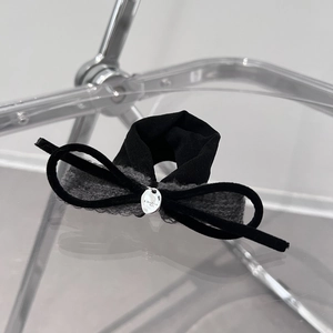 Detail of black velvet bow hair tie featuring a silver oval metal tag with 925 engraving