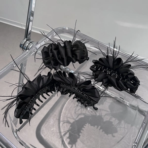 Three-piece black satin cloud hair clips with feathers on a transparent tray