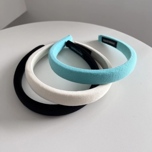 Detail of three thick padded sponge headbands in blue, beige, and black with twill texture