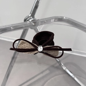 Detailed macro view of dark brown velvet bow scrunchie with metallic silver pendant