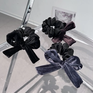 Close-up of elegant velvet bow hair ties in black, dark purple and greyish blue
