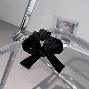 Detail of a black velvet scrunchie bow hanging on a minimalist clear acrylic rack