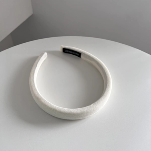 Detail of white ribbed fabric headband with inner handmade label on white display