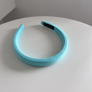 Detail of light blue handmade fabric headband with soft woven texture on a white surface