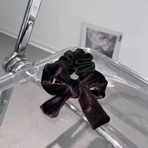 Detail of premium velvet bow hair tie on a minimalist chair showing luxury texture