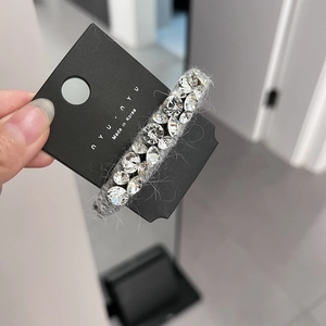 Détail de la barrette en peluche grise avec deux rangées de cristaux sur carte de support