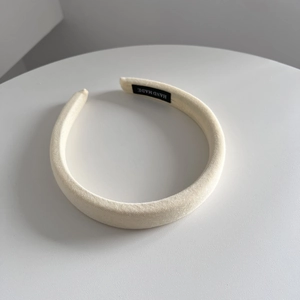 Detail view of cream headband showing knitted texture and Hand Made woven label