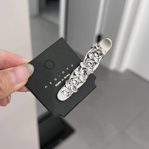 Close-up of silver metal hair clip with seven sparkling oval crystals on black card
