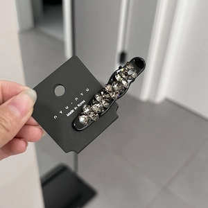 Detail of Korean hair clip with grey rhinestones on black base and nyunyu branding