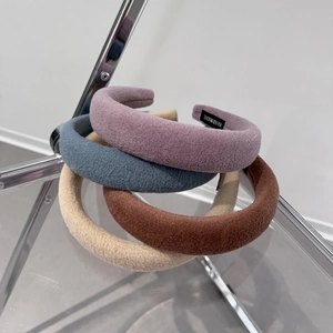 Winter faux wool plush headbands in four colors displayed on a modern chair