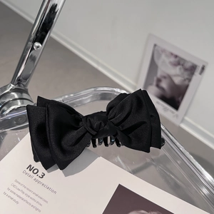 Dettaglio del nastro di raso nero e dei denti in plastica resistenti di questa clip per capelli