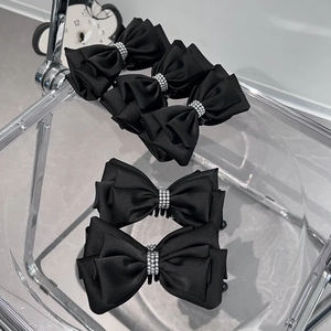 Detail view of five black satin layered bow hair clips with silver pearl center beads