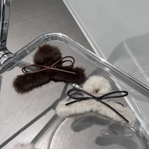 Dettaglio di fermagli per capelli in peluche con fiocco marrone e beige e texture in ecopelliccia