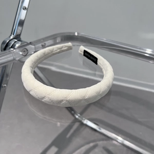 Detailed close-up of the white quilted fabric headband with a black handmade label tag