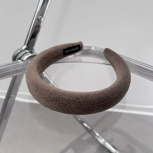 Close-up of a handmade thick coffee brown wool headband with black textile label