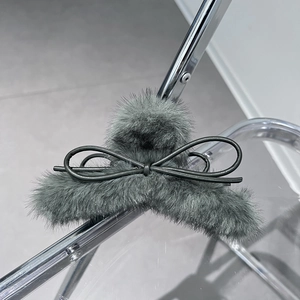 Dettaglio molletta per capelli in peluche grigio con fiocco in pelle nera fine