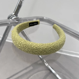 Detail of green woven sponge headband featuring a handmade label on the black inner lining