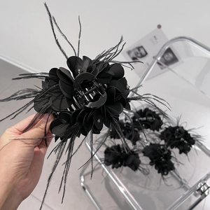 Dettaglio molletta per capelli a petali neri con piume e piccoli strass argentati