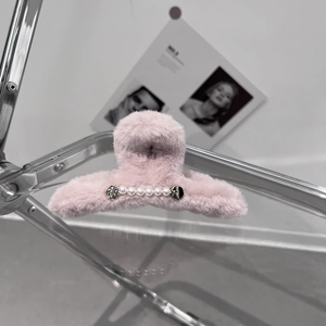 Détail d'une pince à cheveux en fausse fourrure rose avec perles et strass élégants