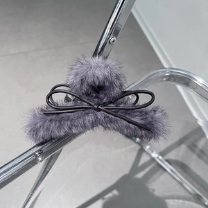 Dettaglio molletta per capelli in peluche grigio-viola con un fiocco marrone scuro