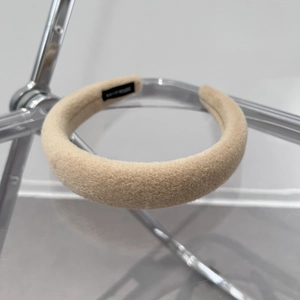 Detail of beige plush padded headband on a metal stand showing soft fabric texture