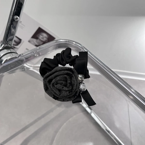 Close-up of black fabric rose hair tie with ribbon bow and sparkling diamond accent
