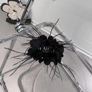 Vista dettagliata della pinza per capelli a fiore nero con petali in tessuto e piume