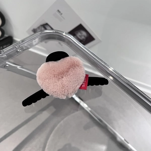 Détail d'une pince à cheveux cœur rose en peluche avec monture noire et petit logo