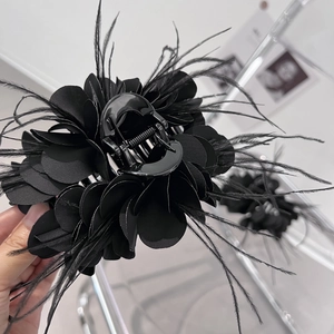 Nahaufnahme der schwarzen Stoffblumen-Haarklammer mit eleganten Federn und Satinblüten