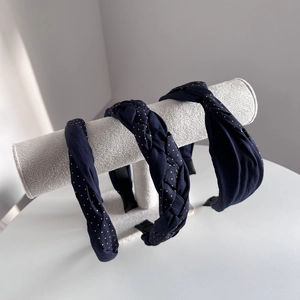 Three-piece navy blue headband set featuring polka dots and braided designs on a stand