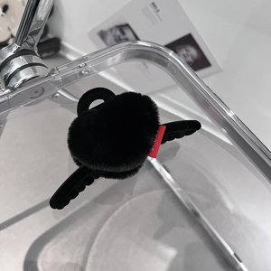 Détail de la pince à cheveux noire en peluche avec étiquette rouge sur fond acrylique