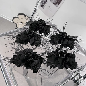Fünf schwarze Feder-Blumen-Haarklammern für Damen-Frisuren auf einem Klarsichttablett