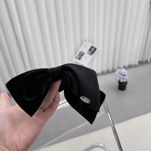 Elegant black velvet bow hair clip with silver metallic logo detail for women