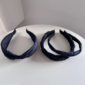 Close-up of navy blue polka dot fabric headbands in knotted and braided styles on a table