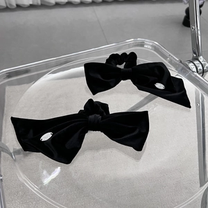 Elegant pair of black velvet bow scrunchies with refined silver metal logo tag