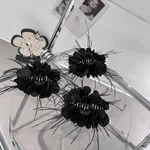 Detail von drei schwarzen Feder-Blumen-Haarklammern mit eleganten Stoffblütenblättern