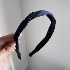 Detailed view of dark blue polka dot braided headband with cross knot and soft fabric