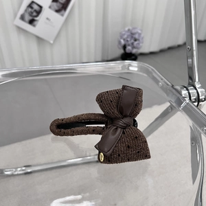 Macro shot of brown polka dot fabric bow clip with gold Love charm and metallic base
